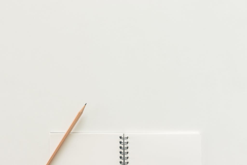 A top view of a spiral notebook with pencil on a neutral light background, ideal for creative workspaces.